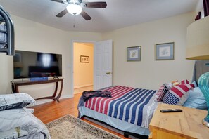 A bedroom with a bed, a television, a ceiling fan, and a door leading to another room. - Hot Tub & Deck! Loganville Group Retreat (Loganville)
