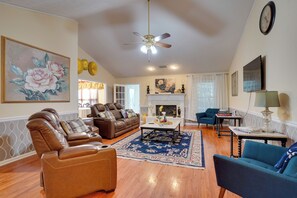 A living room with leather sofas, a blue armchair, a fireplace, and a ceiling fan. - Hot Tub & Deck! Loganville Group Retreat (Loganville)