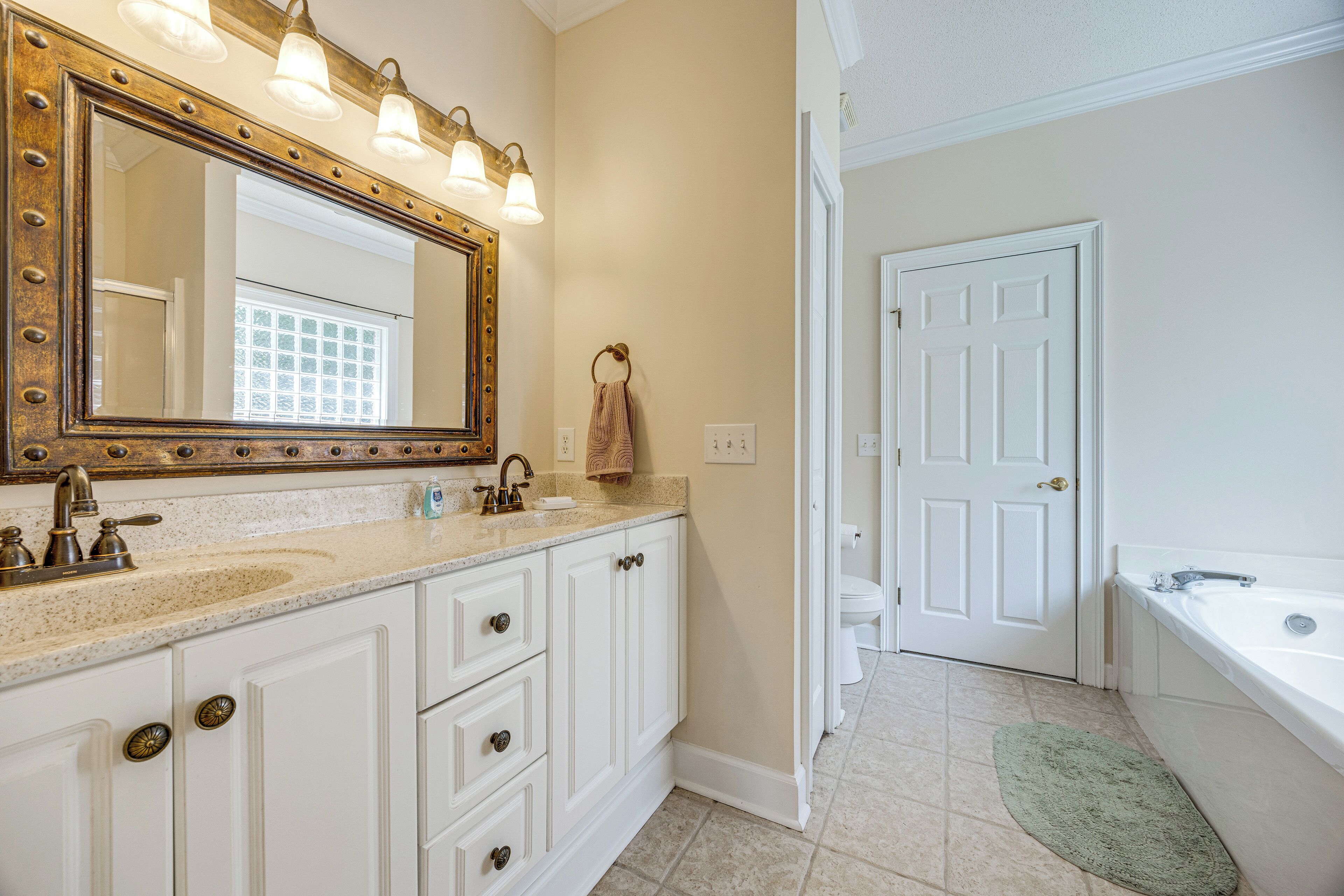 A bathroom with a large mirror, a sink, a towel rack, and a toilet.