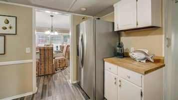 A compact kitchen with a refrigerator, wooden countertop, and white cabinets.