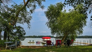 Un entorno junto al lago con un muelle, mesas de picnic y sillas.
