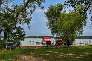 Un entorno junto al lago con un muelle, mesas de picnic y sillas.