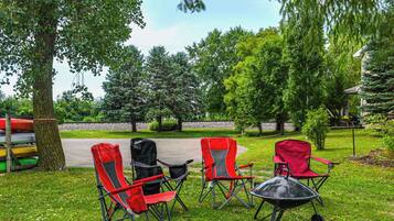 A grassy outdoor area with three red folding chairs and a black wheelbarrow.