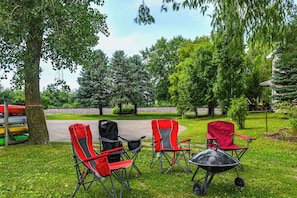 A grassy outdoor area with three red folding chairs and a black wheelbarrow.