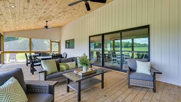 An open-plan living area with a ceiling fan, large windows, and outdoor seating.