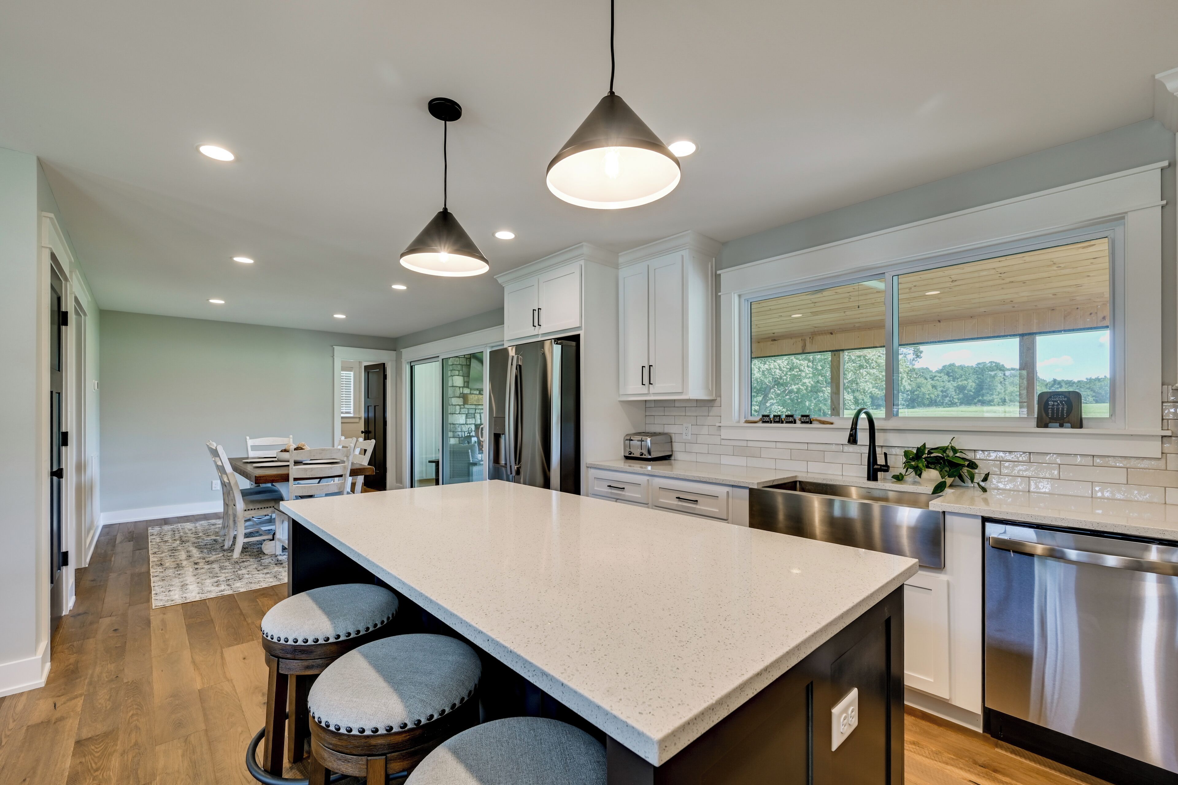 A modern kitchen with a large island, stainless steel appliances, and a view of the outdoors.