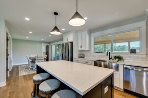 A modern kitchen with a large island, stainless steel appliances, and a view of the outdoors.