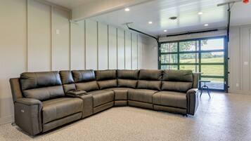 A large sectional sofa in a spacious room with a high ceiling and a large window providing a view of the outdoors.