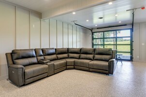 A large sectional sofa in a spacious room with a high ceiling and a large window providing a view of the outdoors.