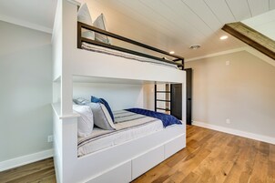 A bunk bed with a white frame, a lower bunk with a striped pillow, and a top bunk with a striped pillow.