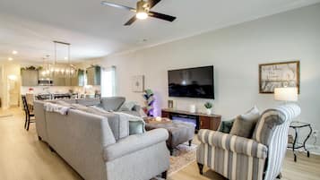 A modern living room with a grey sofa, a striped armchair, and a flat-screen TV mounted on the wall.