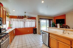 A kitchen with a dishwasher, a stove, and a ceiling fan.