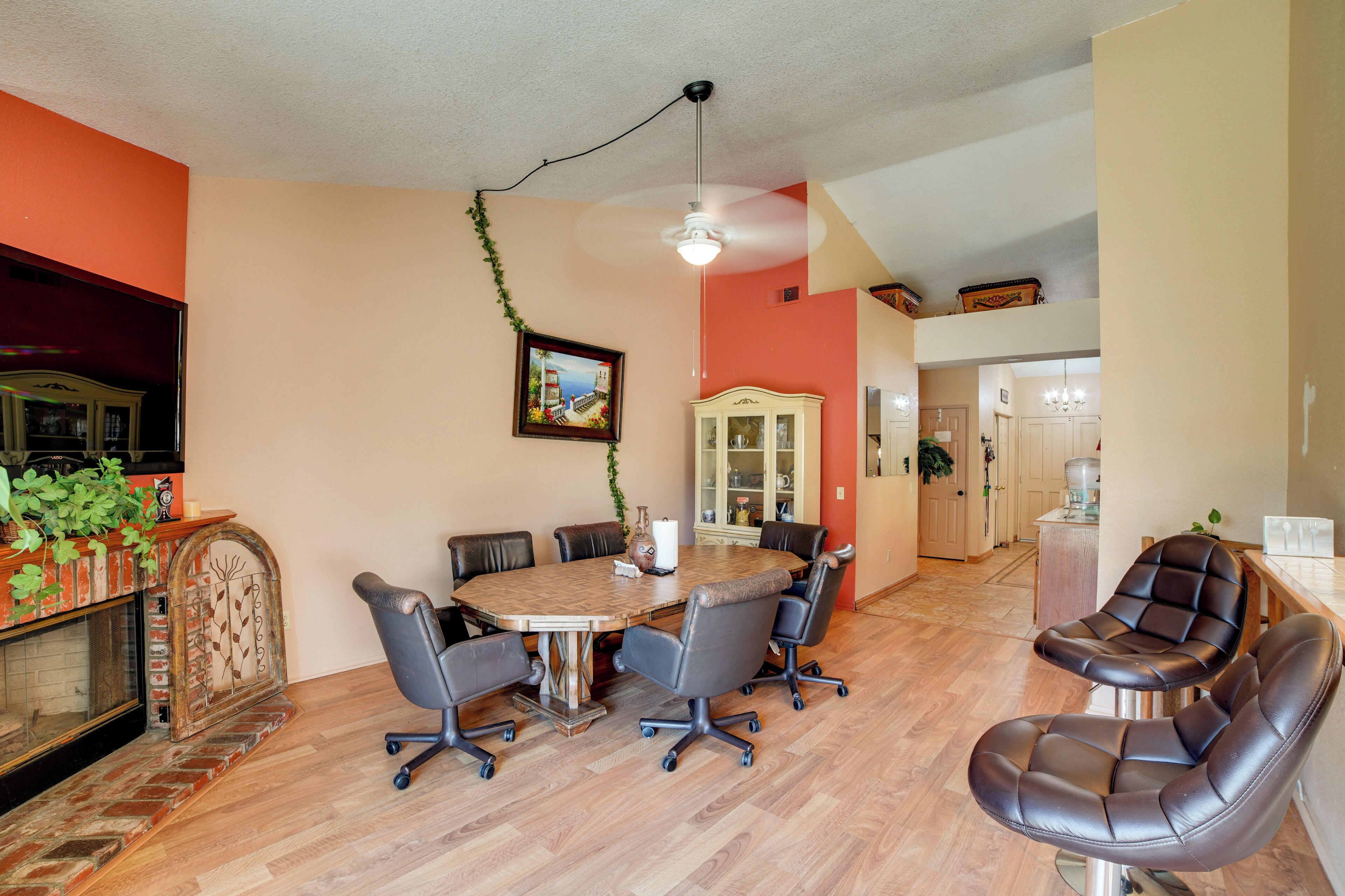 A dining area with a round table, six chairs, and a ceiling fan.