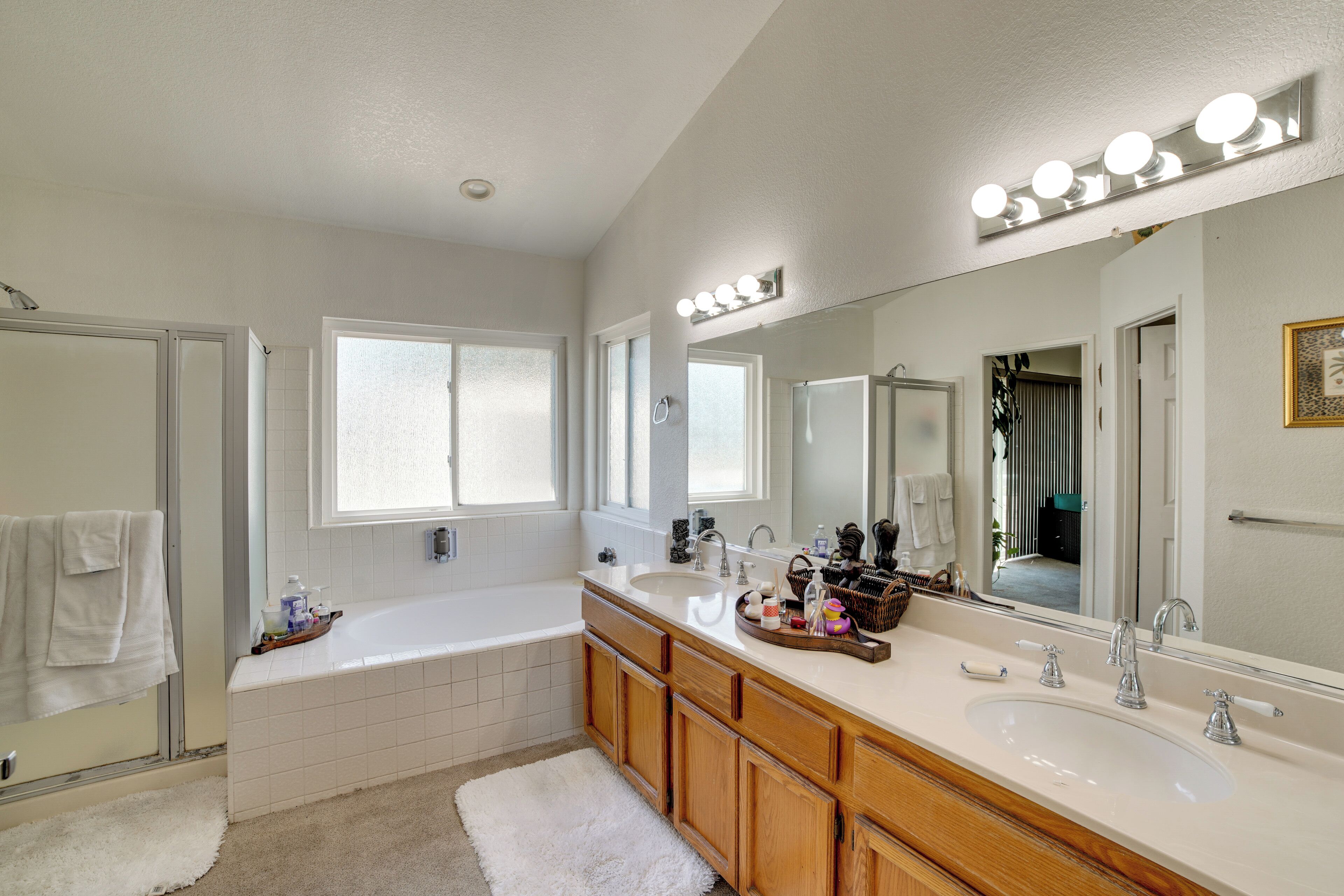 A modern bathroom with a large mirror, vanity, bathtub, and a shower area.