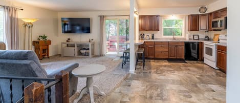A modern kitchen with wooden cabinets, a microwave, and a large window.