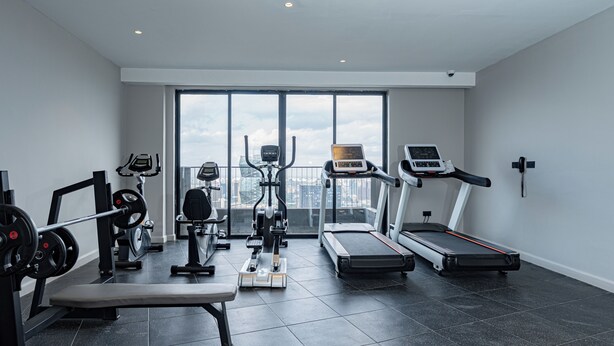 Ein modernes Fitnessstudio mit verschiedenen Trainingsgeräten, einer Hantelbank und einem Laufband.