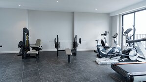 A modern gym with a variety of equipment including a bench press, dumbbells, and cardio machines. - Stylish Studio apartment Upperhill｜Pool & Gym (Nairobi)