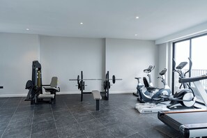Ett modernt gym med en mängd olika träningsredskap, inklusive en bänkpress, hantlar och konditionsmaskiner.