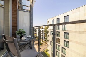 A balcony with a table, chairs, and a potted plant. - Modern Apartment With a Balcony | Air Conditioning (Kraków)