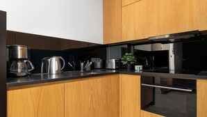 A modern kitchen with wooden cabinets, stainless steel appliances, and a black countertop. - Modern Apartment With a Balcony | Air Conditioning (Kraków)
