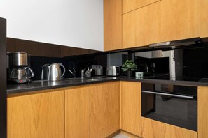 Eine moderne Küche mit Holzschränken, Edelstahlgeräten und einer schwarzen Arbeitsplatte.