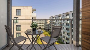 A balcony with a table and chairs, a potted plant, and a view of adjacent buildings. - Modern Apartment With a Balcony | Air Conditioning (Kraków)