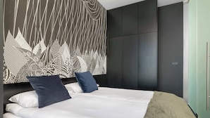 A modern bedroom with a large bed, dark wardrobe, and a patterned wall. - Modern Apartment With a Balcony | Air Conditioning (Kraków)