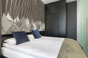 Ein modernes Schlafzimmer mit einem großen Bett, einem dunklen Kleiderschrank und einer Wand mit Muster.