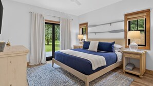 Un dormitorio con cama, mesitas de noche, escritorio y vistas al exterior.