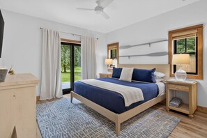 Un dormitorio con cama, mesitas de noche, escritorio y vistas al exterior.