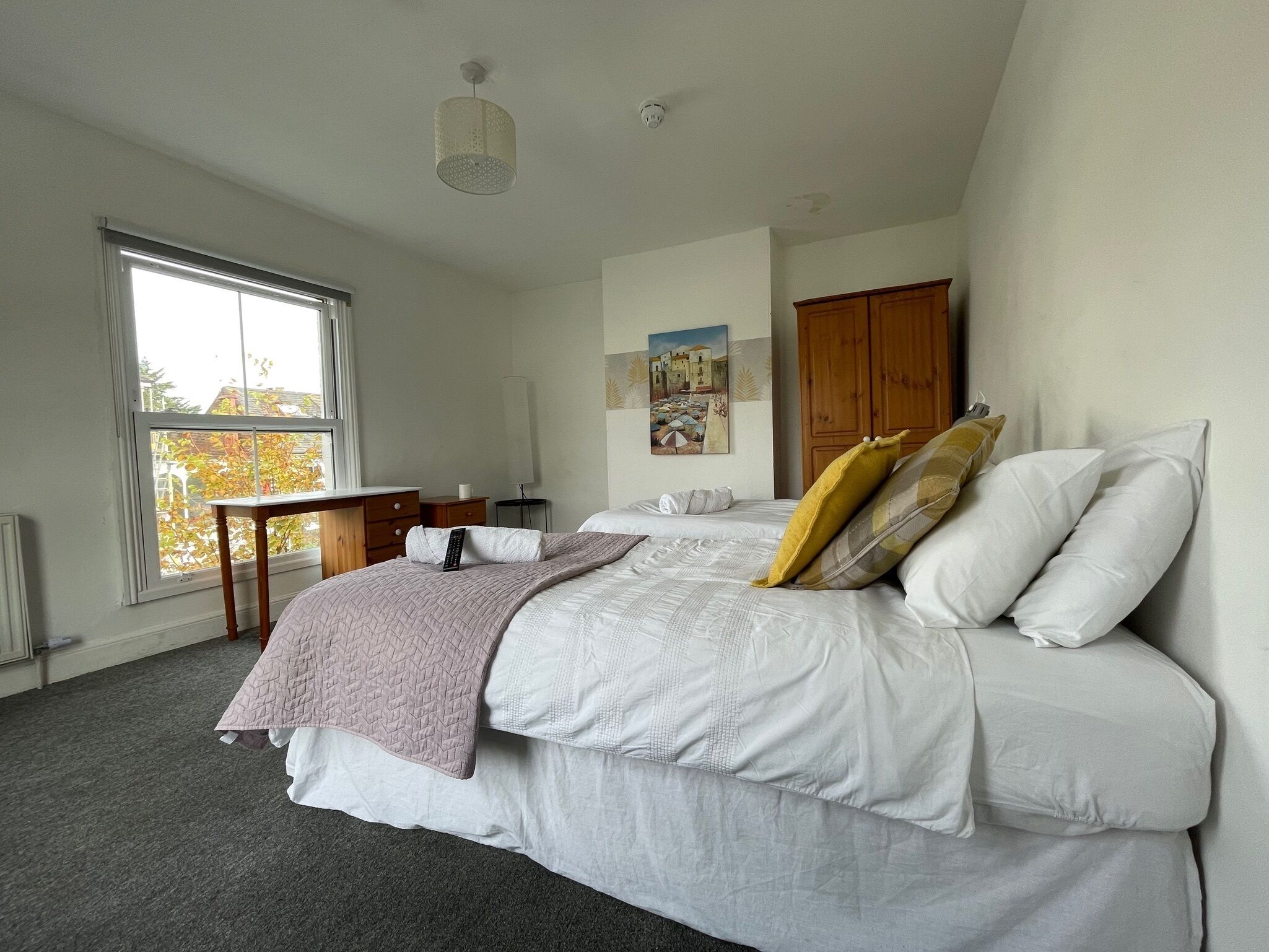 A bedroom with a bed, a desk, a chair, a window, and a door.
