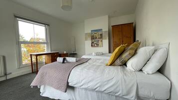 A bedroom with a bed, a desk, a chair, a window, and a door.