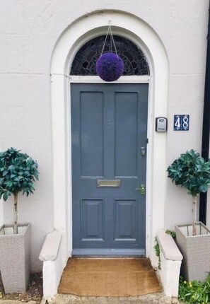 A front door with a mailbox, a number plaque, and two potted plants.