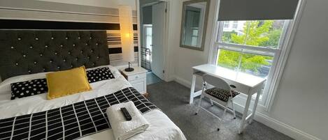Ein Schlafzimmer mit einem großen Bett, einem Schreibtisch und einem Fenster mit Ausblick.