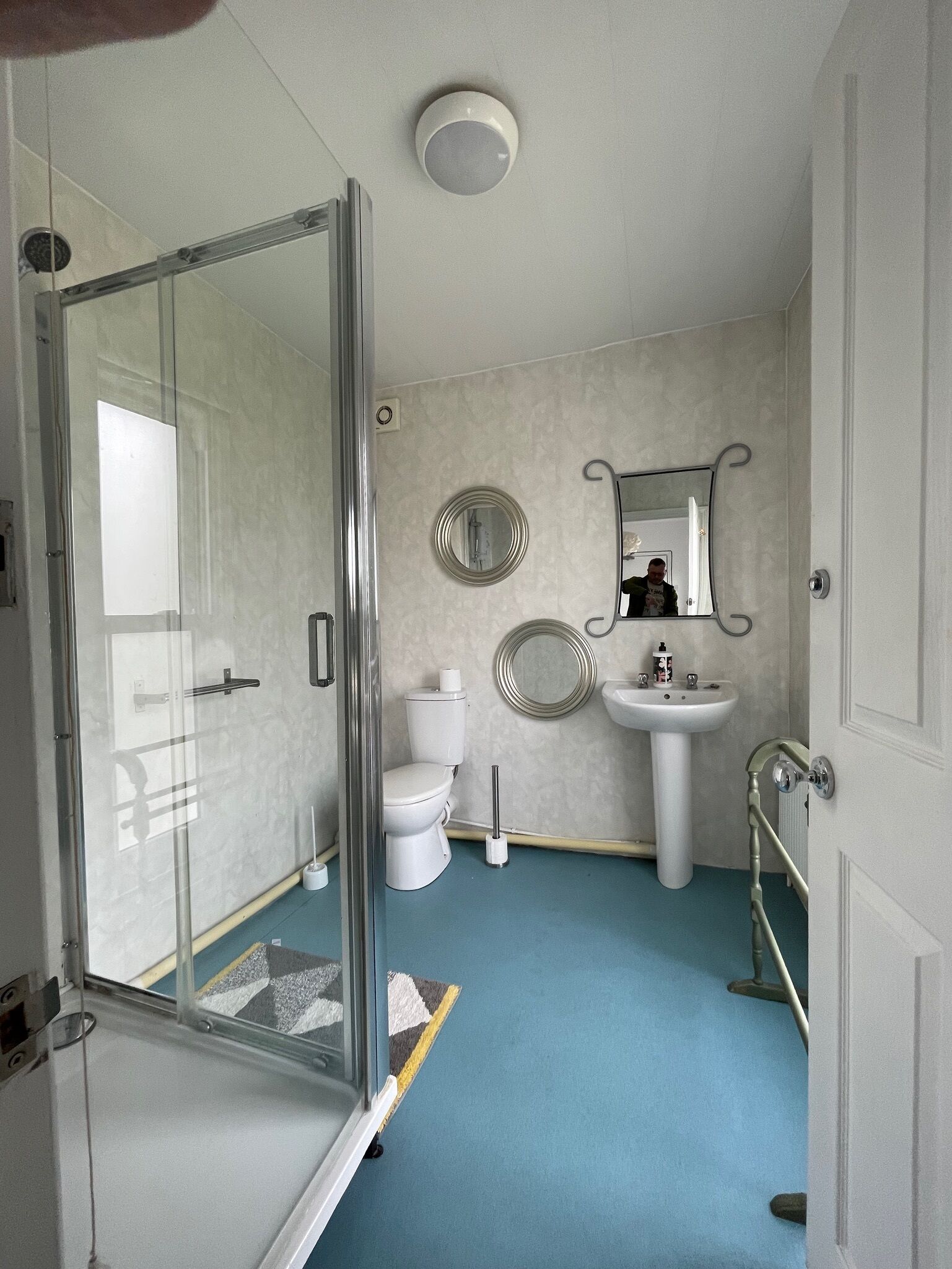 Un baño con cabina de ducha de vidrio, inodoro, lavamanos y espejo.