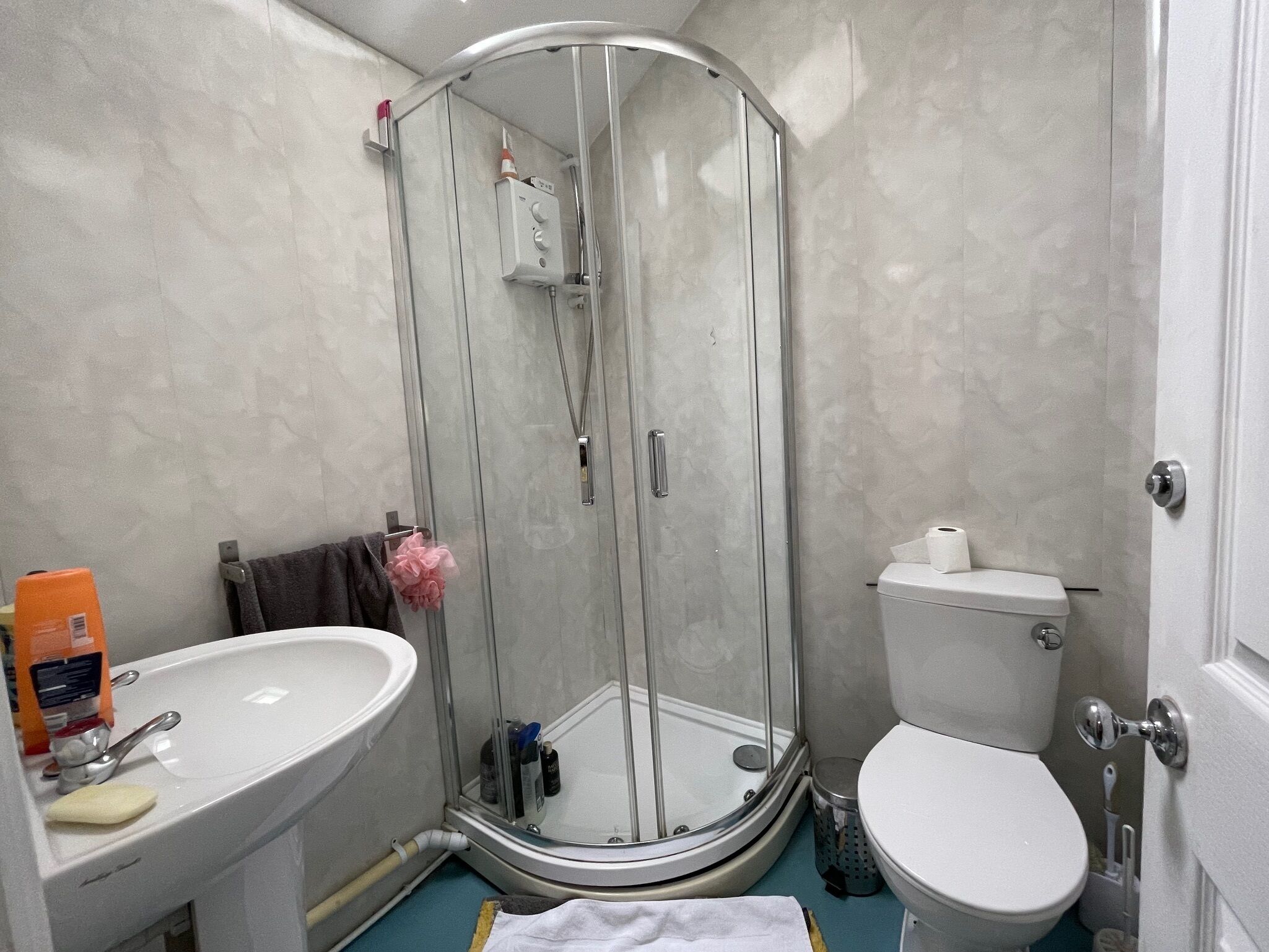 Un baño con cabina de ducha de vidrio, lavamanos e inodoro.