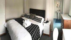 A hotel room with a bed, bedside table, and a bathroom visible through an open door.