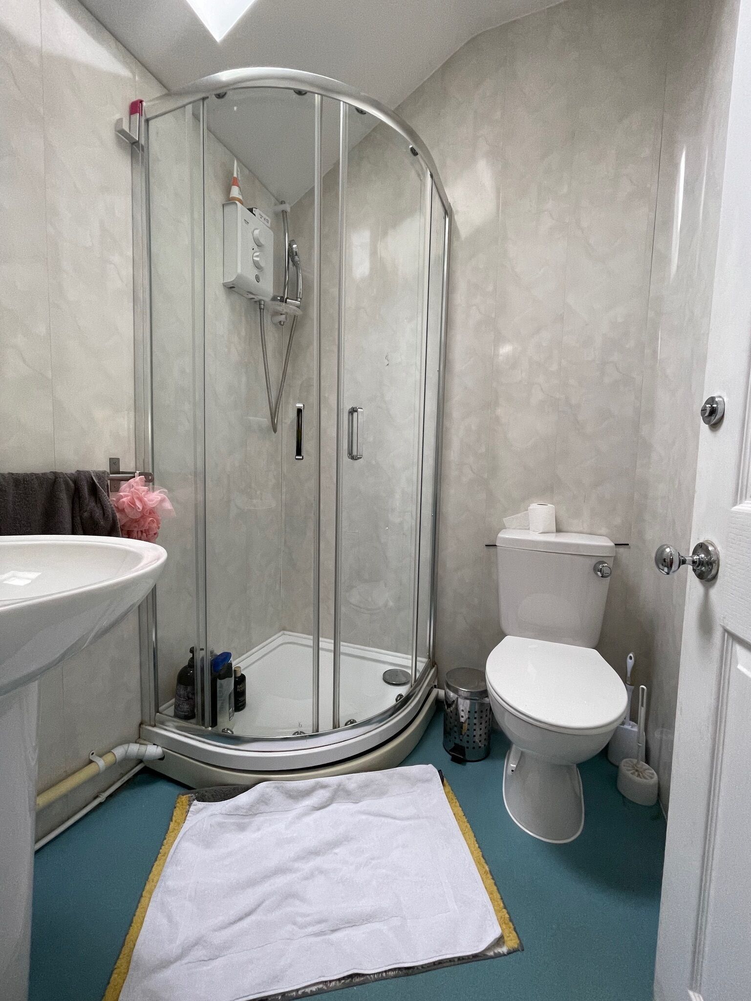 A bathroom with a glass-enclosed shower, a white sink, a toilet, and a blue floor.