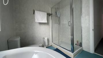 A bathroom with a bathtub, a glass-enclosed shower, and a toilet.