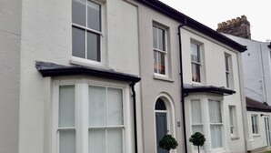 A row of white terraced houses with large windows and a number '48' on the door.