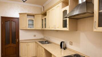 A kitchen with a gas stove, oven, sink, and a modern light fixture.
