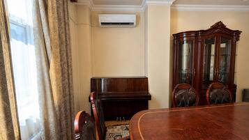 A conference room with a wooden table, chairs, a piano, and a cabinet.