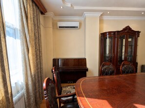 Un salón de conferencias con una mesa de madera, sillas, un piano y un armario.