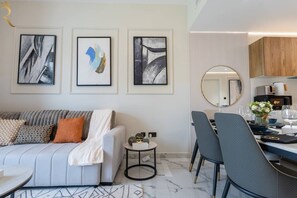 A modern living room with a sofa, a dining area with chairs, and a kitchen in the background. - Luxury 3BR | Sea View | Maryah Vista (Abu Dhabi)