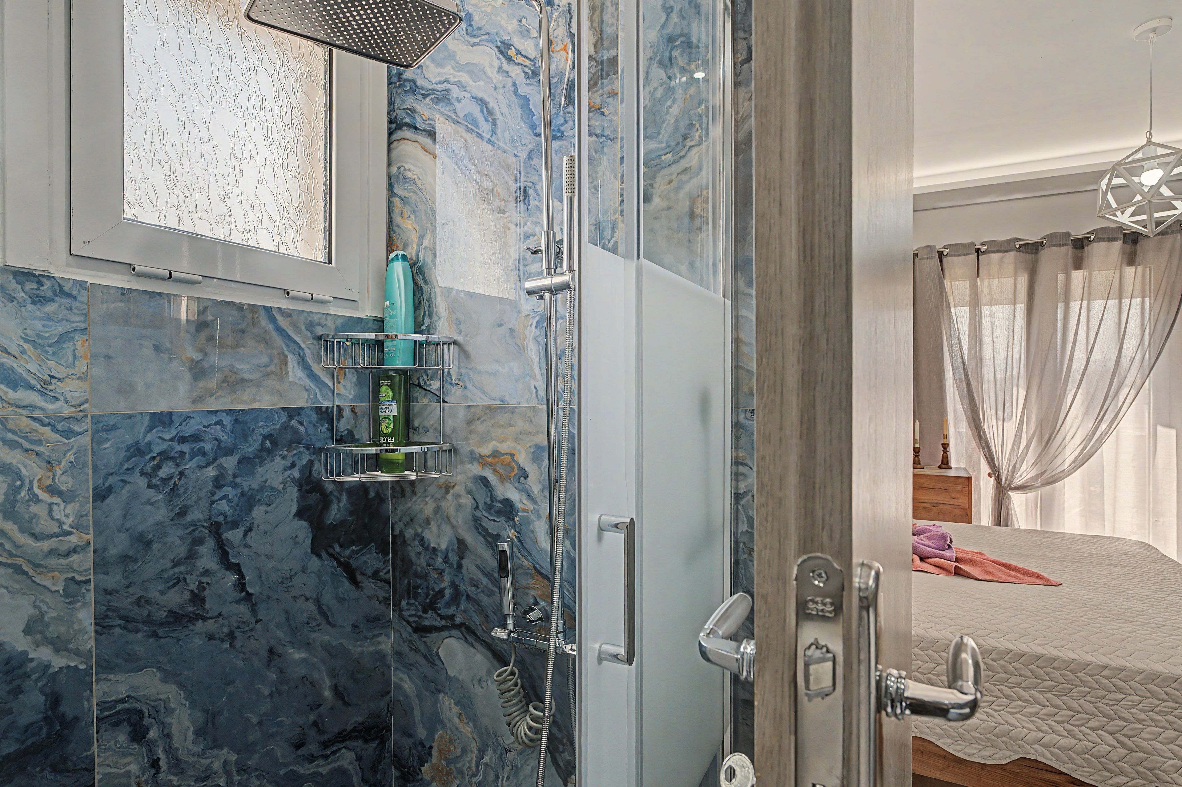 Une salle de bain équipée d’une douche, d’un miroir et d’une étagère où sont rangés les articles de toilette.