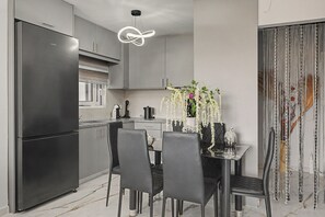 Une cuisine moderne dotée d’un réfrigérateur encastré, d’une table à manger avec des chaises et d’un luminaire suspendu.