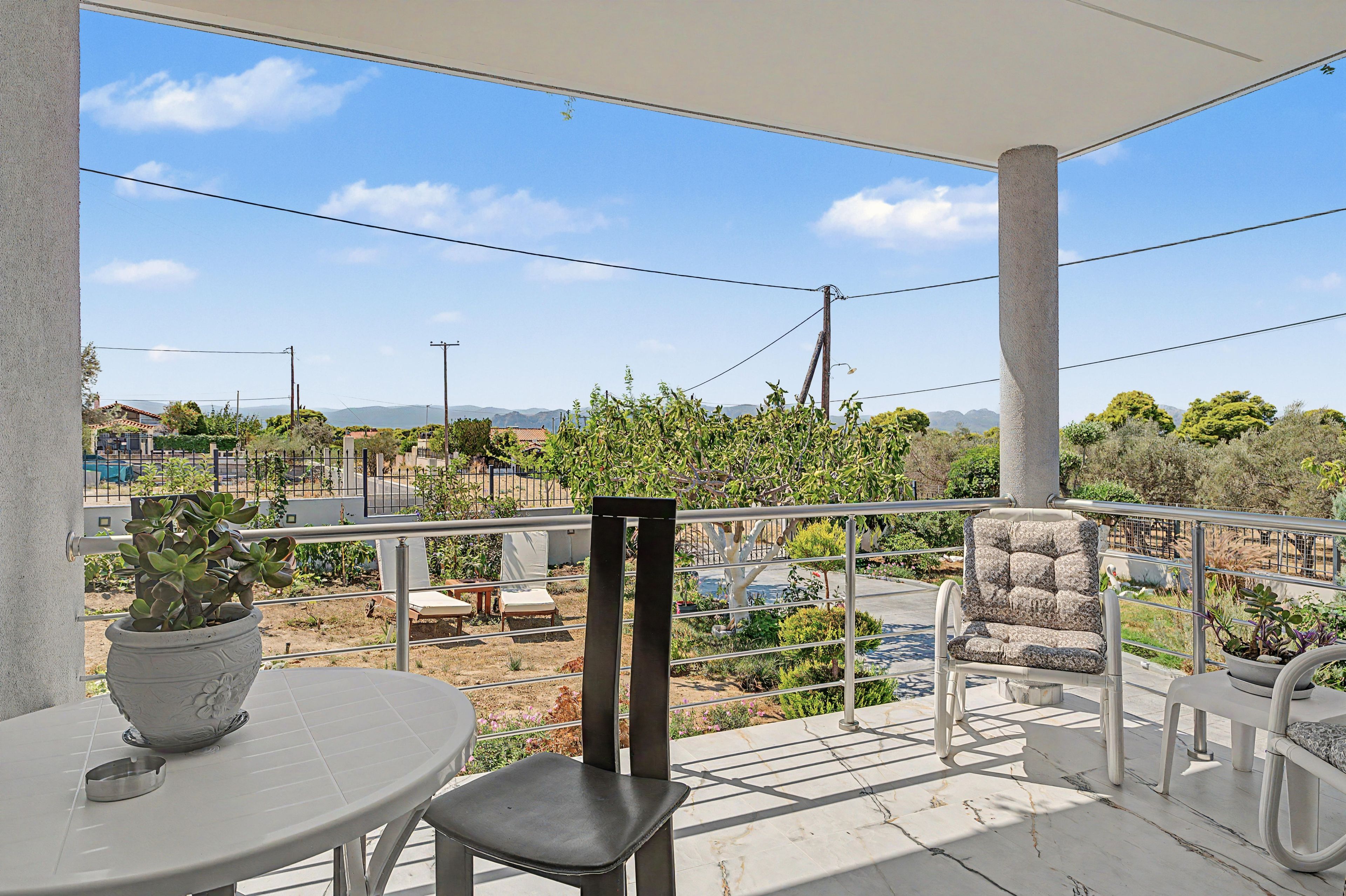 Ein Balkon mit Blick auf eine Wohngegend, einem Blumentopf und Gartenmöbeln.