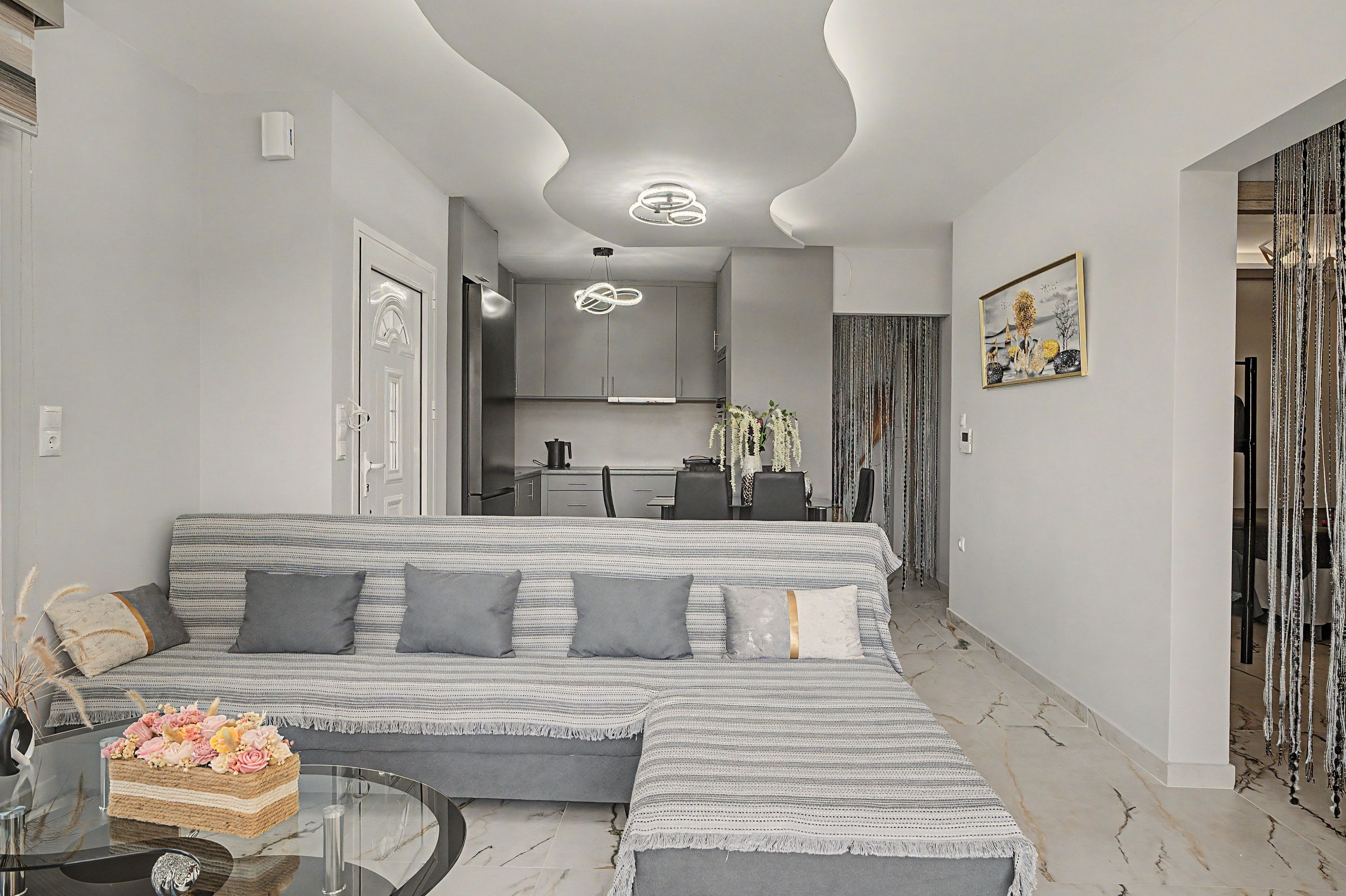 A modern living room with a sofa, a coffee table, and a decorative vase with flowers.
