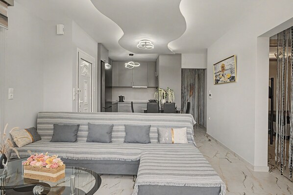 A modern living room with a sofa, a coffee table, and a decorative vase with flowers.