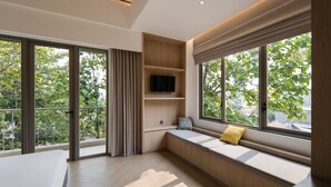A modern interior with large windows, a built-in bench, and a flat-screen TV. - Cove Svasa (Jakarta)